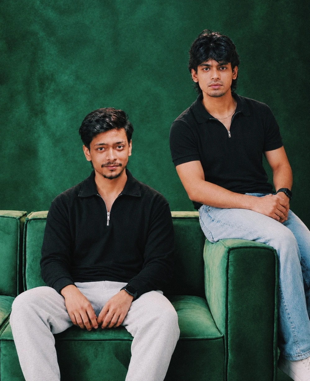 Azwah founders Rakib and Fahmid sitting on a green sofa